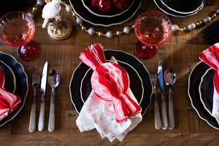 A christmas table decorated with festive decorations such as a pink and red christmas sweet, garlands and tree decorations.