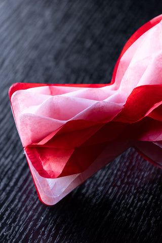 Detail shot of the end of one of the Set Of 3 Pink & Red Honeycomb Sweets on a dark wooden table.