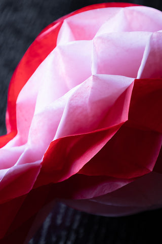 Close-up of one of the Set Of 3 Pink & Red Honeycomb Sweets on a dark wooden table.