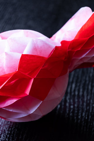 Close-up of one of the Set Of 3 Pink & Red Honeycomb Sweets on a dark wooden table.