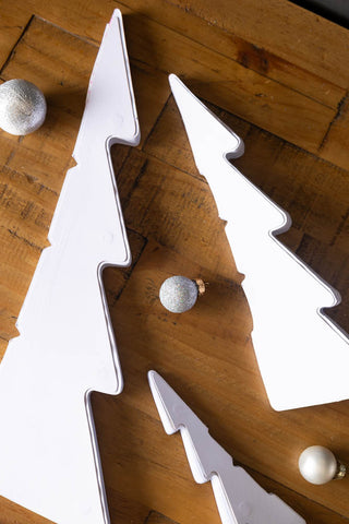 The Set Of 3 White Paper Trees unassembled, displayed on a wooden surface with some baubles.