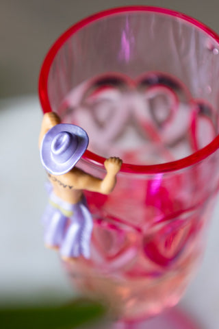 A purple cowboy drinks marker on the edge if a pink champagne flute.