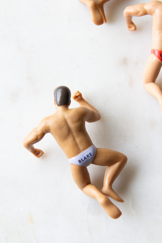 Close-up of one of the Set Of 4 Hunk Wine Glass Charms face down on a white surface with others in shot, seen from above.