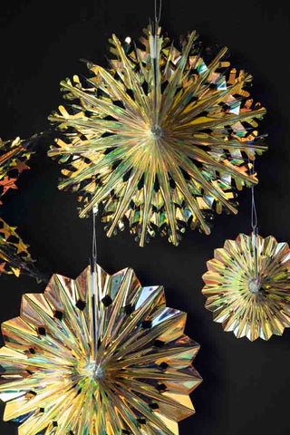 Close-up of four of the Set Of 5 Iridescent Star Decorations, displayed on a dark wall.