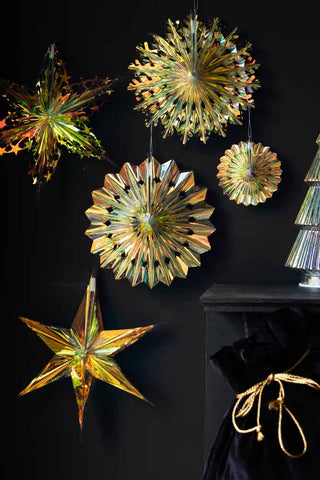 The Set Of 5 Iridescent Star Decorations displayed on a black wall next to a fireplace, styled with a Christmas sack and a tree decoration.