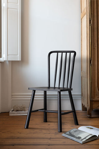 One of the Set of 2 Classic Wooden Frame Dining Chairs displayed on a wooden floor next to a window, with some books, next to a wooden storage unit.