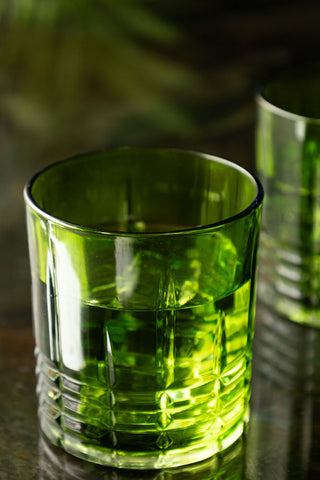 One of the Set of 2 Green Whiskey Embossed Glasses displayed on a dark surface, with the other glass in the background.