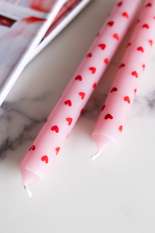 Close-up of the Set of 2 Red & Pink Heart Dinner Candles on a table with some magazines.