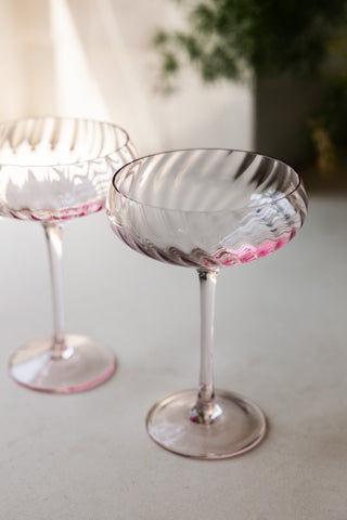 The Set of 2 Scalloped Coupe Cocktail Glasses styled together on a white work surface.