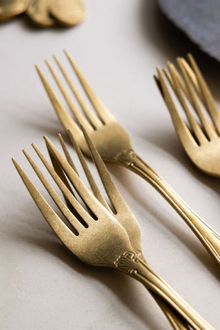 A close-up of the tines of antique-style gold forks