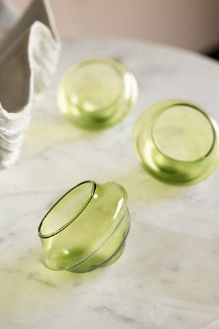 The Set Of 3 Pale Green Glass Tea Light Holders displayed on a white table.