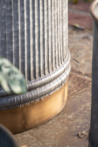 Close-up of the base of one of the Set of 3 Industrial Style Iron Planters, displayed on a patio.