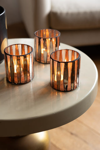 The Set of 3 Metallic Mosaic Effect Glass Tealight Holders styled with lit tealights inside, on a round table.