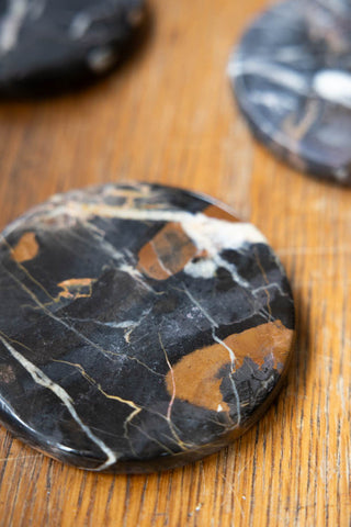 Close-up of the Set of 4 Black Marble Coasters on a wooden surface.