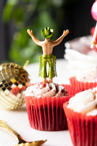 One of the Set of 4 Cowboy Cake Toppers seen from behind, styled in a cupcake amongst others, with a disco ball decoration and a spoon.