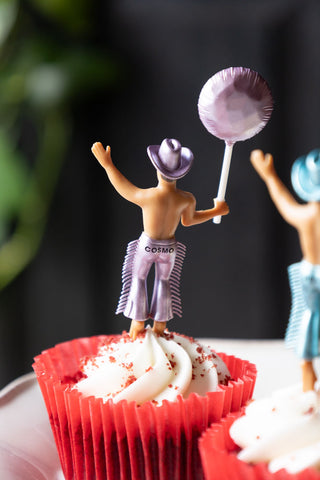 Close-up of one of the Set of 4 Cowboy Cake Toppers, seen displayed in a cupcake from behind, revealing the name 'Cosmo' written on it.