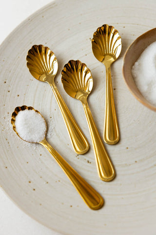 The Set of 4 Gold Shell Teaspoons styled on a table.