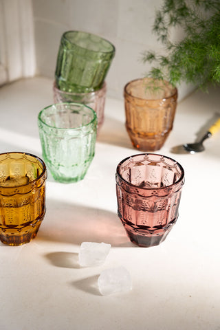 The Set of 6 Colourful Vintage-Style Glass Tumblers on a worktop in the sun, styled with ice, a spoon and a plant.