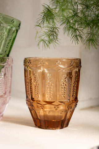 Close-up of one of the Set of 6 Colourful Vintage-Style Glass Tumblers, styled with two others and a plant in the background.