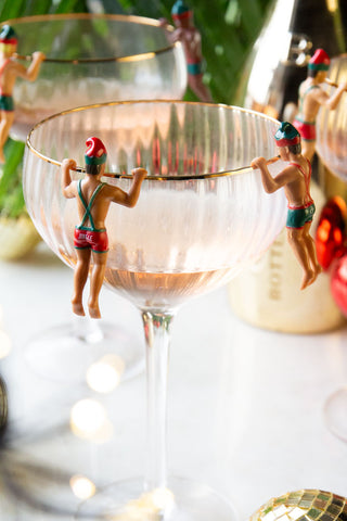 Close-up of some of the Set of 6 Christmas Elf Cowboy Drink Markers displayed on the edge of champagne glasses.