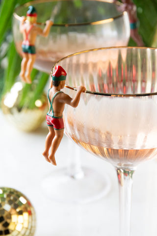 Detail shot of one of the Set of 6 Christmas Elf Cowboy Drink Markers displayed on the edge of a champagne glass.