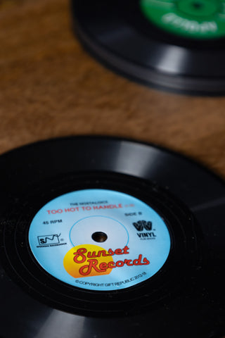 Close-up of some of the Set of 6 Vinyl Style Coasters, displayed on a wooden surface.