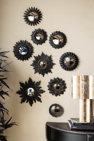 The Set of 9 Ornate Antique Black Framed Mirrors styled on a neutral wall, above a plant and table with books and a lamp on.