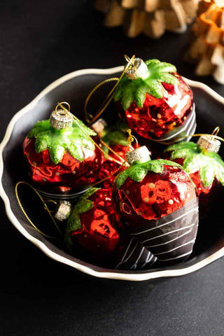 A black and white bowl filled with the set of six chocolate dipped strawberry decorations.