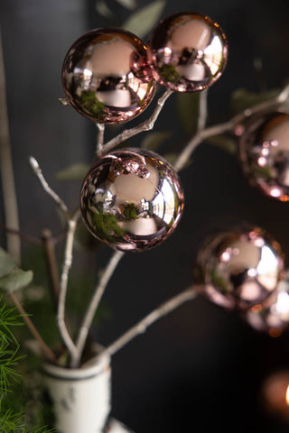 Close-up of the Shiny Pink Bauble Spray displayed in a vase with some greenery.