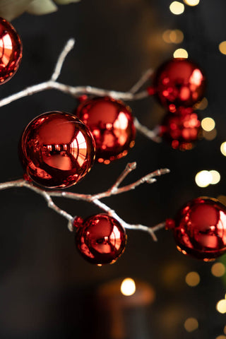 Close-up of the Shiny Red Bauble Spray in front of a dark wall and some fairy lights.