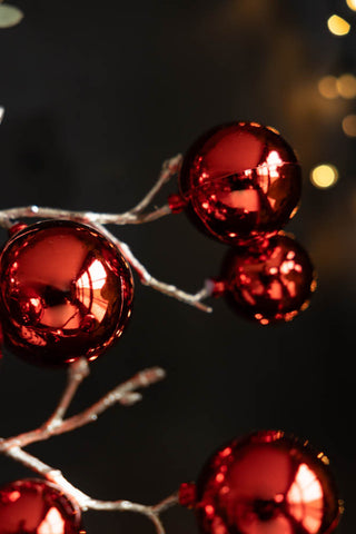 Detail shot of the Shiny Red Bauble Spray in front of a dark wall and some fairy lights.