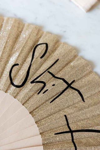 Close-up shot of the text on the Shit Hot Black & Gold Glitter Fan.