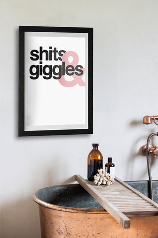 The Shits & Giggles Art Print - Unframed in a black frame, displayed on the wall above a bath with a bath tray and bathroom accessories.