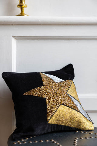 The Shooting Star Cushion on a stool, leaning against a wall.