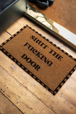 A lifestyle image of the Shut The Fucking Door Doormat, displayed in an entrance hallway