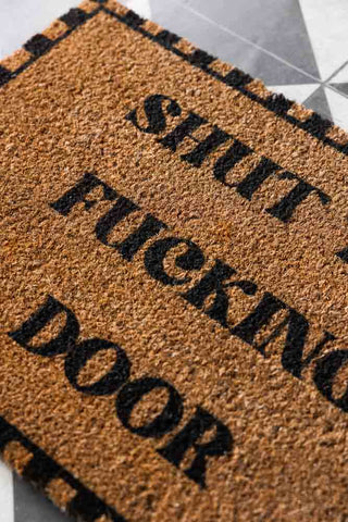 Close-up of the Shut The Fucking Door Doormat.