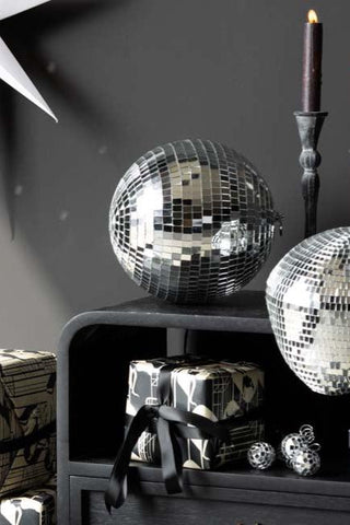 The Silver Disco Ball - 20cm styled on a black unit surrounded by presents, decorative accessories and other disco items.