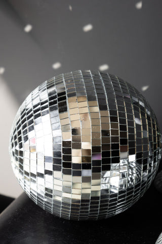 The Silver Disco Ball - 20cm on a black unit, casting reflections onto the wall behind.