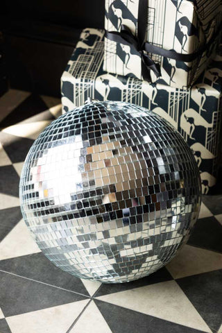 The Silver Disco Ball - 30cm styled on the floor in front of some presents.