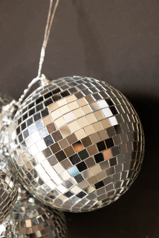 Detail shot of one of the disco balls of the Silver Disco Ball Cluster Decoration, in front of a black wall.