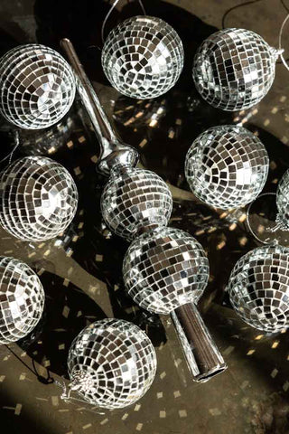 An angled image of Silver Disco Ball Tree Decoration set with sunlight catching the mirrors