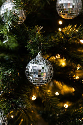 The Silver Disco Ball & 10 Disco Ball Christmas Tree Decoration Set hung on a christmas tree with christmas lights.