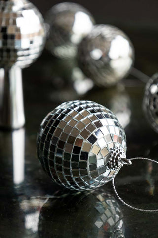 A Silver Disco Ball Christmas Tree Decoration styled on a dark surface with multiple disco decorations in the background.