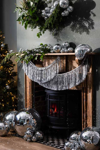 Lifestyle image of a disco christmas living room with the Melty Disco Ball on a wooden fireplace.