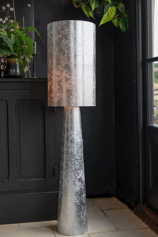 The Silver Leafed Effect Floor Lamp switched on and displayed in the corner of the room.