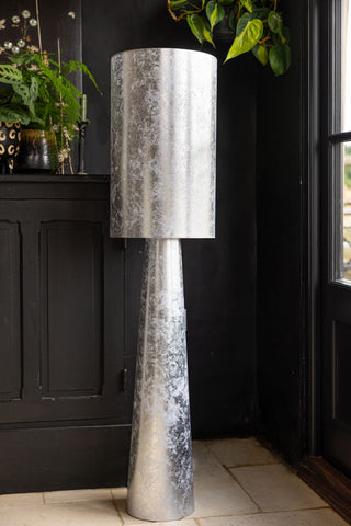 The Silver Leafed Effect Floor Lamp styled in the corner of a black room.