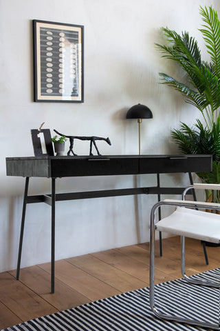 The Sleek Black Desk With Two Drawers styled in an office space with various home accessories and a plant.