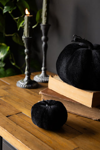 Small Black Velvet Pumpkin with candles and large pumpkin on top of books