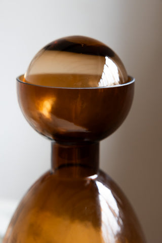 Close-up of a bronze glass bottle with the round lid inside.