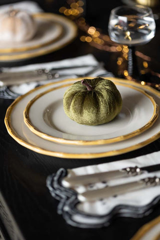 The Small Green Velvet Pumpkin styled on two white plates as part of a tablescape.